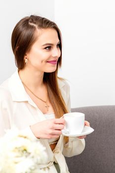 Female caucasian client with a cup of coffee in his hands smiling at a doctor's appointment