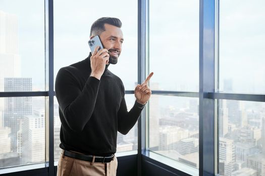 young man with a smartphone standing near the window. close-up.