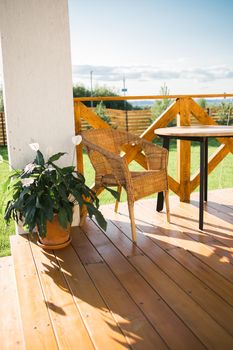 Cozy wooden terrace of country house or cottage with garden view - table and chair for relaxing evening. High quality photo
