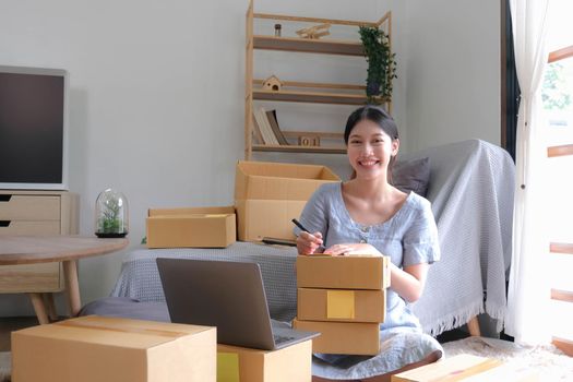 SME entrepreneur Small business entrepreneurs Online selling ideas,Happy Young Asian business owner work on computer and a boxs at home,delivery SME procurement package box deliver to customers,.