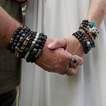 Senior man en woman holding hands. They wear lava stone and other breaded bracelets.