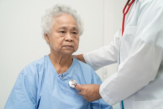 Doctor with stethoscope checking senior or elderly old lady woman patient while sitting on a bed in the nursing hospital ward, healthy strong medical concept.