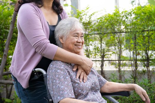 Caregiver daughter help Asian senior or elderly old lady woman on electric wheelchair in park.