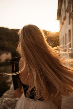 Blonde long hair, nature summer happy adult girl with long blond hair developing in the wind in nature. Dressed in a black top, white skirt