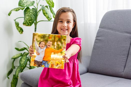 little girl holding photo canvas with autumn. Beautiful girl with canvas
