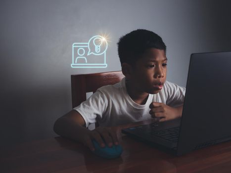 Close up The boy sits staring at the laptop and his hand is holding the mouse. educational concept, educational information search, copy space