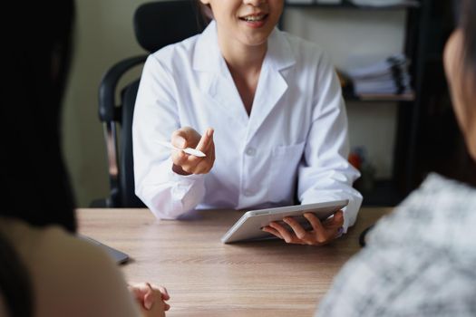 Portrait of a doctor advising clients on health issues holding a tablet to work and talking to patients who come to treatment.