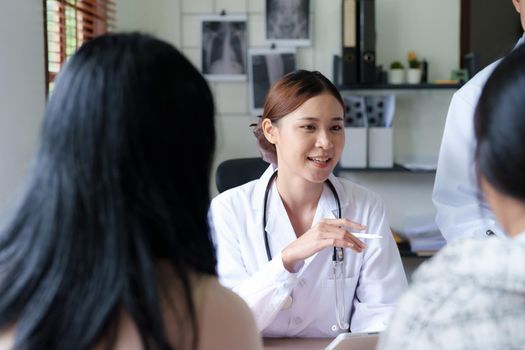 Portrait of a doctor advising clients on health issues holding a tablet to work and talking to patients who come to treatment.