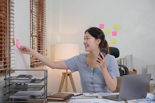 Business asian woman using smartphone for do math finance on wooden desk in office, tax, accounting, financial concept.