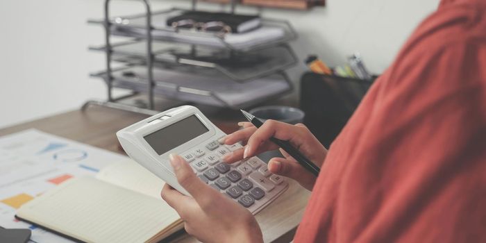 Business woman using calculator and laptop for do math finance on wooden desk in office and business working background, tax, accounting, statistics and analytic research concept.