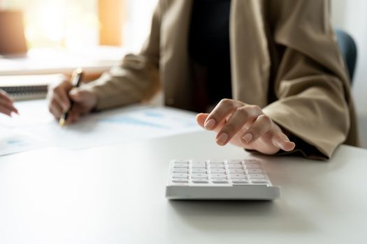 Close up bookkeeper woman working about financial with calculator at her office to calculate expenses, Accounting concept.