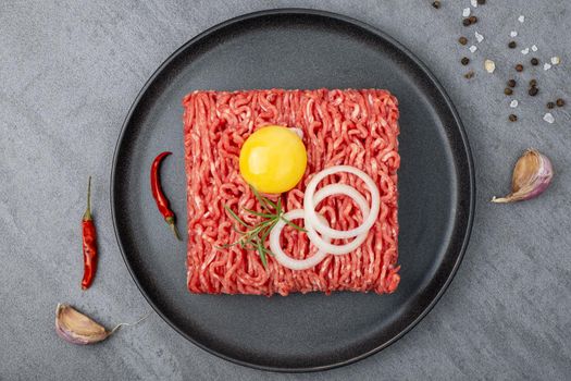 Minced meat lies on a black ceramic plate. View from above. Selective focus.