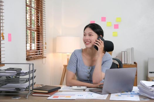 Business asian woman using smartphone for do math finance on wooden desk in office, tax, accounting, financial concept.