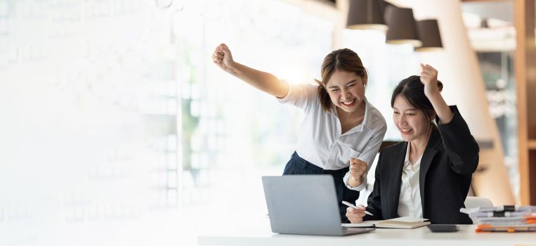 Two asian woman excited business team celebrate corporate victory together in office.