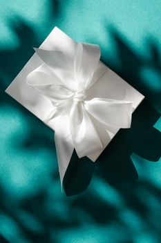 Anniversary celebration, shop sale promotion and bridal surprise concept - Luxury holiday white gift box with silk ribbon and bow on emerald green background, luxe wedding or birthday present