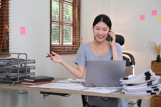 Business asian woman using smartphone for do math finance on wooden desk in office, tax, accounting, financial concept.