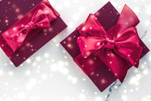 New Years Eve celebration, wrapped luxury boxes and cold season concept - Winter holiday gifts with cherry silk bow and glowing snow on frozen marble background, Christmas presents surprise