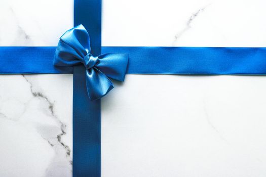 Happy holidays, festive decoration and brand sale promotion concept - Blue silk ribbon and bow on luxury marble background, holiday flatlay backdrop