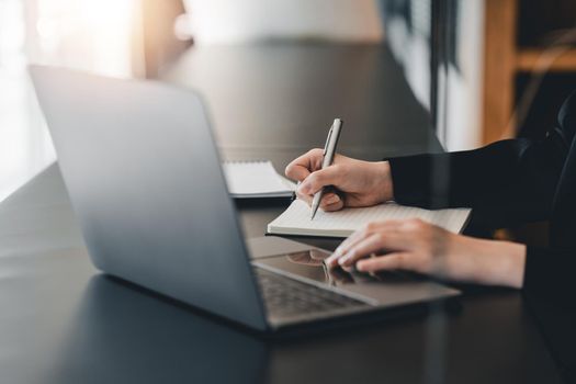 Cropped photo of woman writing making list taking notes in notepad working or learning on laptop indoors- educational course or training, seminar, education online concept.