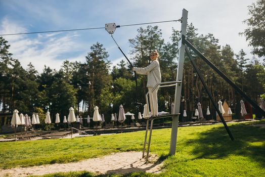 A young woman wants to go bungee from the tower in the rope park
