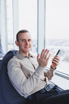 A businessman communicates with his clients by phone while sitting in a modern office workspace. Focused businessman sits alone in a modern workspace.