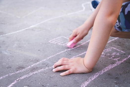 Children draw with chalk on the road. Children's creativity on the street. Entertainment in nature.