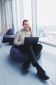 Concentrated young businessman looking at laptop screen, information online or working remotely online at home office, communicating remotely with client or study.