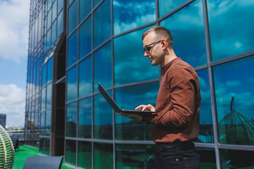 Cheerful businessman, formally dressed, pleased with received good news about contract details, sitting on office terrace with laptop, successful male entrepreneur