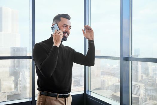 smiling business man talking on his smartphone near the window.