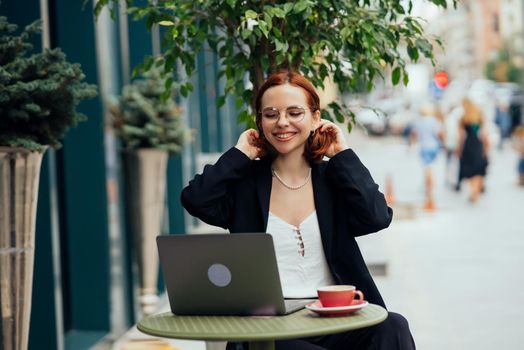 Happy young woman in a street cafe looks into the camera