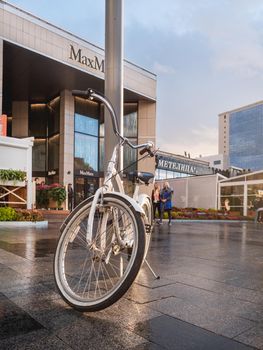 MOSCOW, RUSSIA - September 17, 2022. White bicycle parked on Novy Arbat. Wet pavement of famous street after rain.