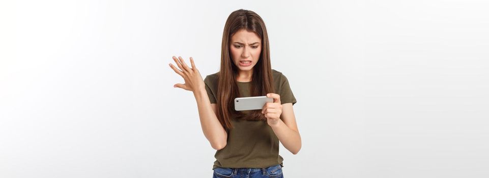 Happy attractive brunette girl joying win in video game on smartphone, isolated over grey background.