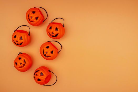 Halloween decorations with pumpkin baskets on orange background. Halloween concept. Flat lay, top view, copy space