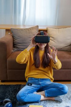 portrait of a young Asian woman using virtual reality simulator headset at home.