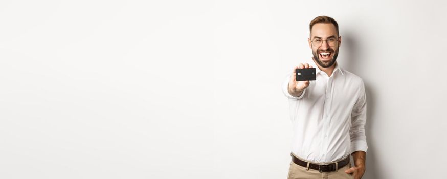 Excited caucasian man in glasses showing credit card, concept of shopping.