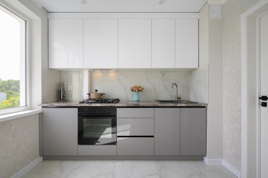 White and grey small modern domestic kitchen interior and furniture
