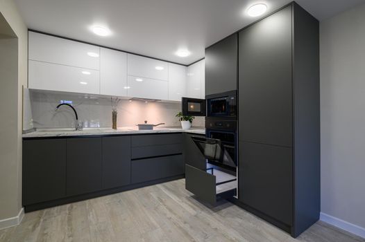 Showcase interior of modern simple trendy dark grey and white kitchen, drawers retracted