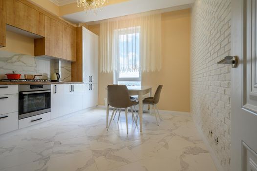 Modern white and wooden furniture in yellow kitchen with dining table with yellow walls and white marble floor