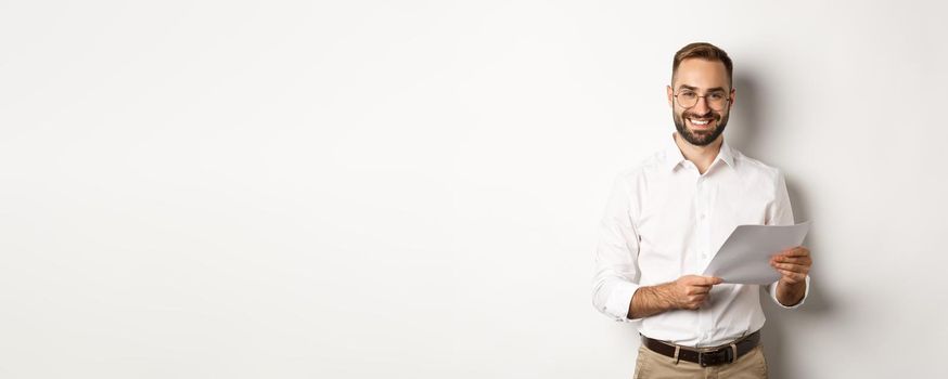 Employer looking satisfied with work, reading documents and smiling pleased, standing over white background.