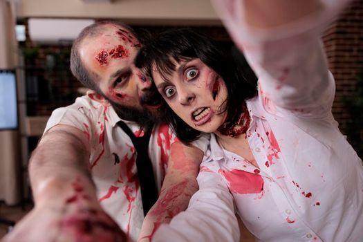Portrait of grunge monsters couple in business office, hunting people to eat brain and looking evil terrifying. Aggressive dangerous walking dead corpses eerie monsters attacking workplace.