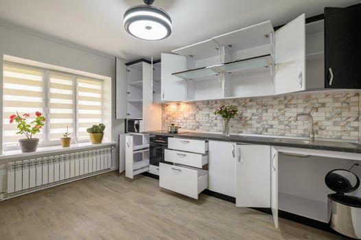 Interior renovation showcase of well designed modern trendy white kitchen, cabinet doors open, drawers retracted