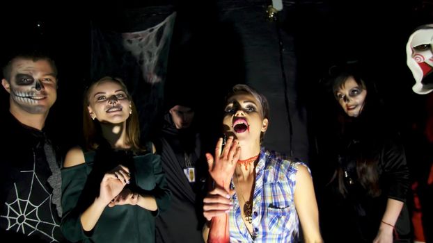 Halloween party, night, twilight, in the rays of light, young people frighten the spectators, everyone is dressed in scary costumes for Halloween. High quality photo