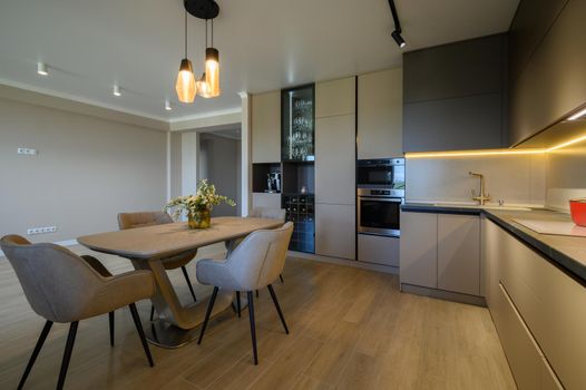 Large modern grey luxurious kitchen with dining table in studio apartment interior