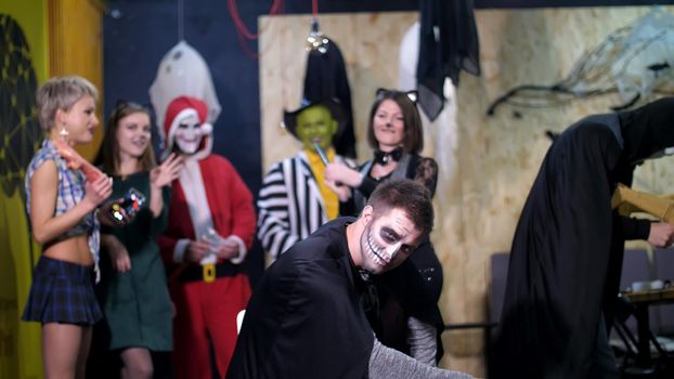 Halloween party, photo session, young people dressed up in scary costumes and made a horrific make-up. they are having fun, in the background Halloween scenery is seen. High quality photo