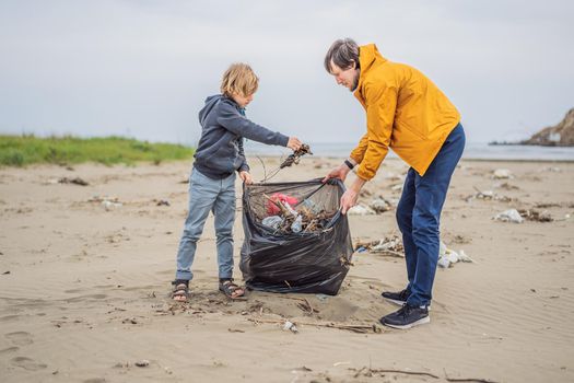 Dad and son in gloves cleaning up the beach pick up plastic bags that pollute sea. Natural education of children. Problem of spilled rubbish trash garbage on the beach sand caused by man-made.