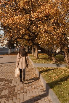 A stylish brunette woman walks around the autumn city. The season is autumn.