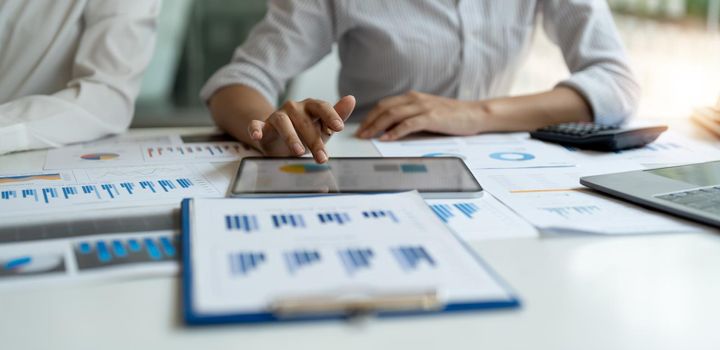 Business colleagues working and analyzing financial figures on a digital tablet.