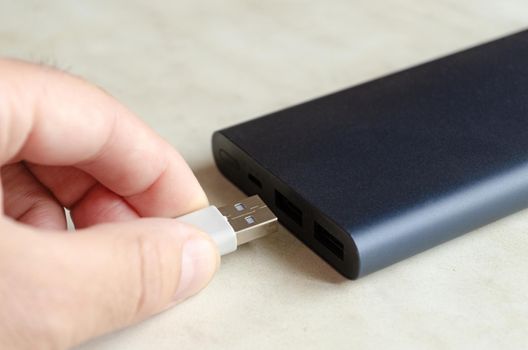 man inserts usb cable into powerbank.Charging mobile gadget.