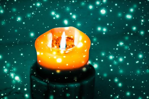 Happy holidays, greeting card and winter season concept - Orange holiday candle on green sparkling snowing background, luxury branding design for Halloween, New Years Eve and Christmas