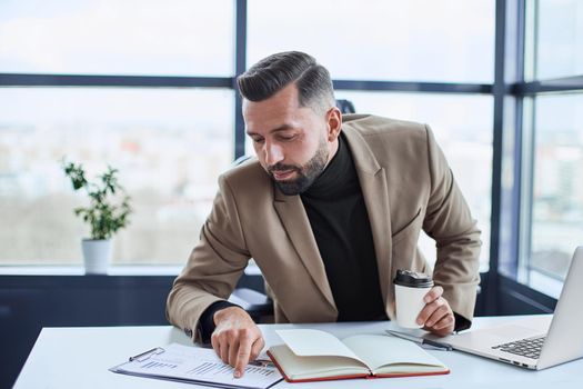 businessman with takeaway coffee analyzing a financial document. close-up.